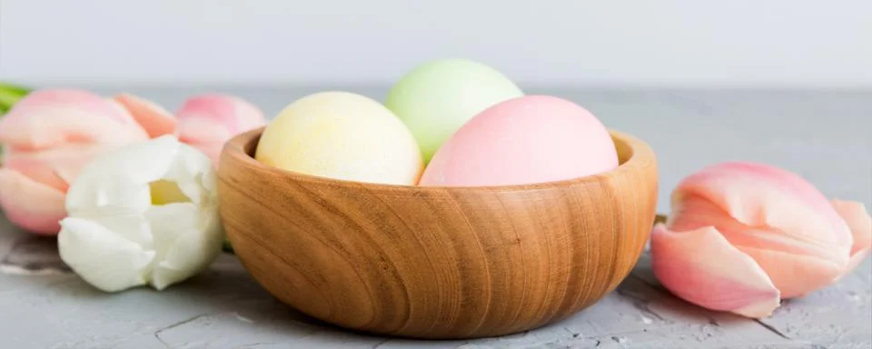 Happy Easter composition. Easter eggs in basket on colored table with yello.. Stock Photos
