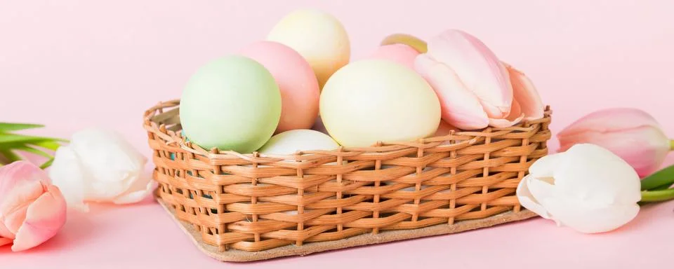 Happy Easter composition. Easter eggs in basket on colored table with yello.. Stock Photos