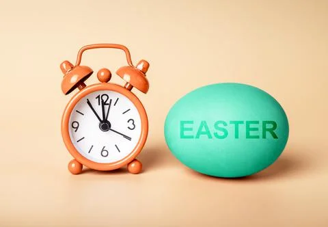 Happy Easter concept. Alarm clock and painted egg Stock Photos
