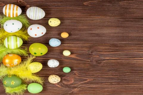 Happy Easter concept. Colorful Easter eggs with bright feathers on a dark wooden Stock Photos