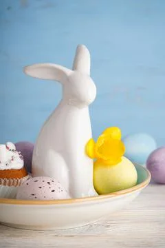 Happy Easter concept. Easter bunny ceramic and eggs with flower on a wooden b Stock Photos