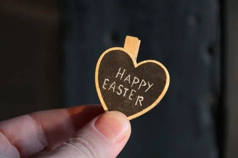 Happy easter concept. The hand holds a heart with the inscription. Stock Photos
