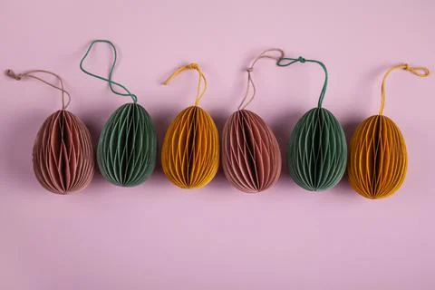 Happy easter concept. Multicolored easter eggs made of paper on a pastel pink Stock Photos