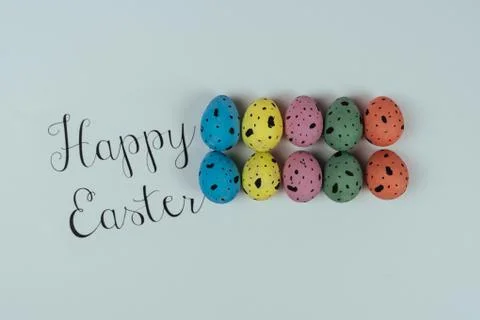 Happy Easter concept. Painted Easter quail eggs with greeting card on white Stock Photos