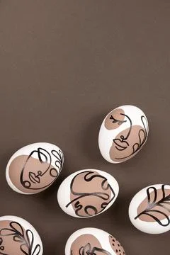 Happy Easter concept. Surreal faces on eggs on brown background. Art und Onli Stock Photos