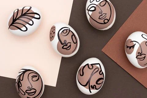 Happy Easter concept. Surreal faces on eggs on brown background. Art und Onli Stock Photos