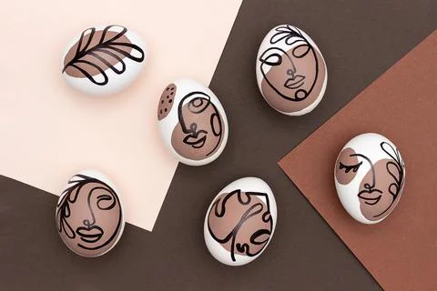 Happy Easter concept. Surreal faces on eggs on brown background. Art und Onli Stock Photos