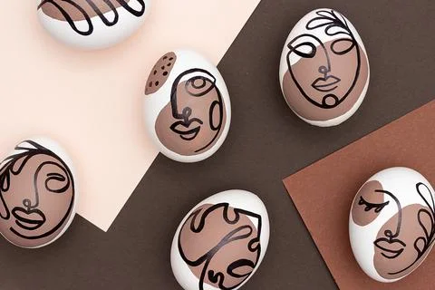Happy Easter concept. Surreal faces on eggs on brown background. Art und Onli Stock Photos