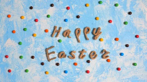Happy Easter congratulation among dragee on blue background. Stop motion. Stock Footage 123904067