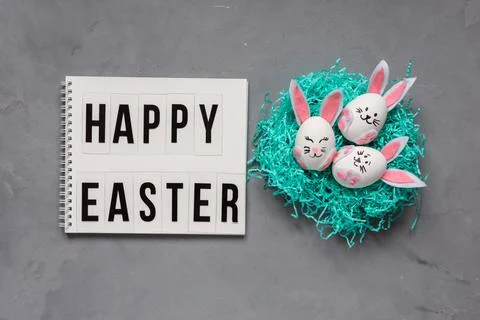 Happy Easter congratulation, Easter eggs painted as bunnies on the nest on the Stock Photos