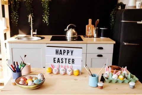 Happy Easter congratulation on the table, painted colorful eggs next to it, in Stock Photos