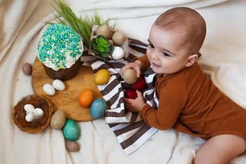 Happy Easter. Cute and happy little baby playing with Easter eggs and cake at Stock Photos