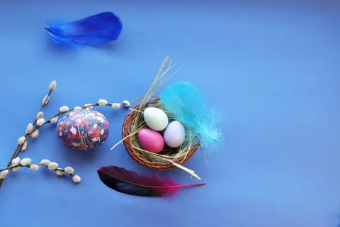 Happy Easter, decor, basket with painted eggs, bright feathers Stock Photos