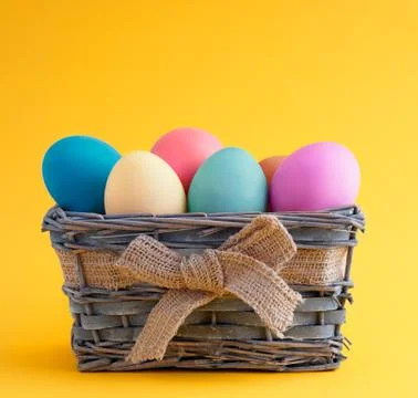 Happy easter, dyed colored eggs in the basket on the one-color background. Stock Photos