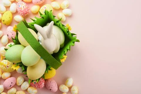 Happy Easter. Easter eggs and rabbit in green basket on pink background wit.. Stock Photos