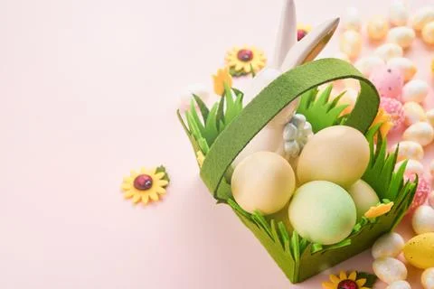 Happy Easter. Easter eggs and rabbit in green basket on pink background wit.. Stock Photos