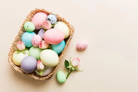 Happy Easter. Easter eggs in basket on colored table with yellow roses. Natur Foto stock