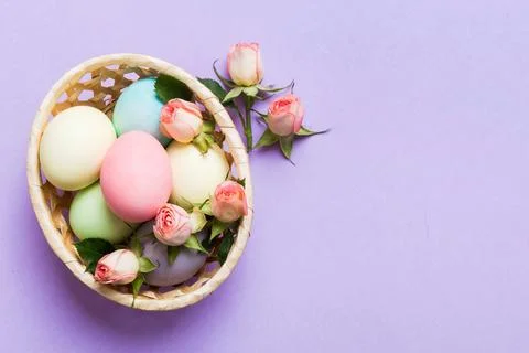 Happy Easter. Easter eggs in basket on colored table with yellow roses. Natur 库存照片