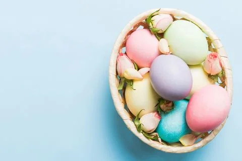 Happy Easter. Easter eggs in basket on colored table with yellow roses. Natur 库存照片