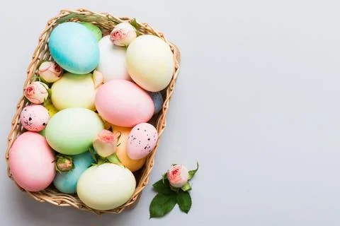 Happy Easter. Easter eggs in basket on colored table with yellow roses. Natur Stock Photos