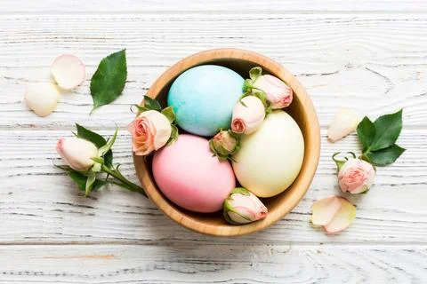 Happy Easter. Easter eggs in basket on colored table with yellow roses. Natur 스톡 사진