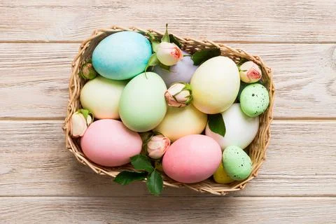 Happy Easter. Easter eggs in basket on colored table with yellow roses. Natur Stock Photos