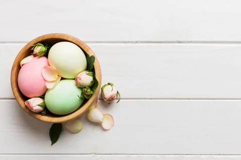 Happy Easter. Easter eggs in basket on colored table with yellow roses. Natur 库存照片