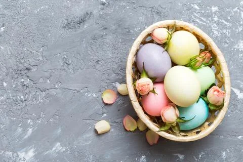 Happy Easter. Easter eggs in basket on colored table with yellow roses. Natur Stock Photos