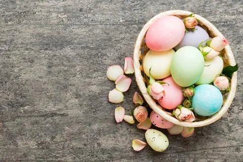 Happy Easter. Easter eggs in basket on colored table with yellow roses. Natur Stock Photos