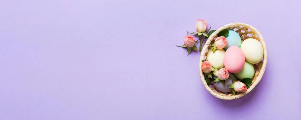 Happy Easter. Easter eggs in basket on colored table with yellow roses. Natur Stock Photos