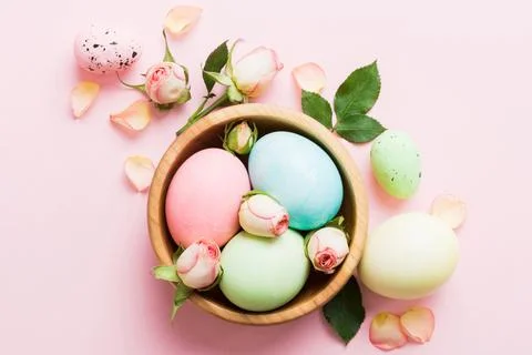 Happy Easter. Easter eggs in basket on colored table with yellow roses. Natur Stock Photos