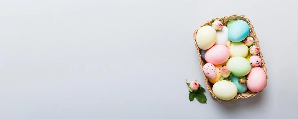 Happy Easter. Easter eggs in basket on colored table with yellow roses. Natur Stock Photos
