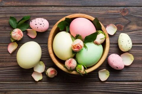 Happy Easter. Easter eggs in basket on colored table with yellow roses. Natur Stock Photos