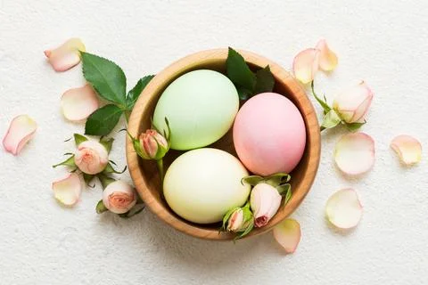 Happy Easter. Easter eggs in basket on colored table with yellow roses. Nat.. Stock Photos