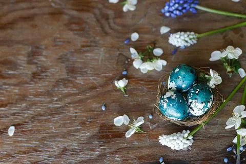 Happy Easter! Easter eggs in nest with spring flowers flat lay on rustic wo.. Stock Photos