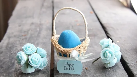 Happy easter. Egg on rustic table and a basket with a blue label Stock Footage 74154704