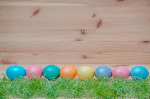 Happy easter eggs pastel colored with grass on the wooden background Stock Photos