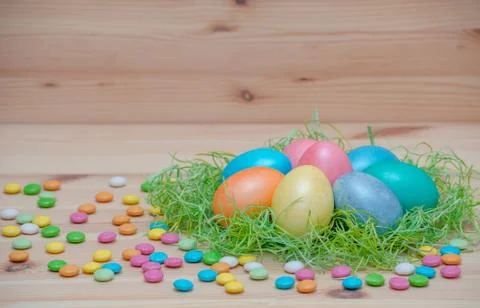 Happy easter eggs pastel colored in a nest with candle on the wooden background Stock Photos