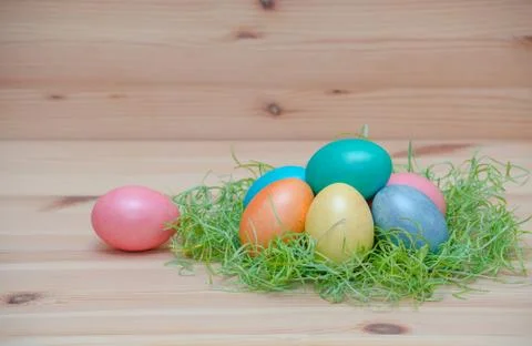 Happy easter eggs pastel colored in a nest with candle on the wooden background Stock Photos