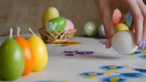 Happy Easter. Female hand putting on the table two easter eggs. colorful candles Video stock 106146947