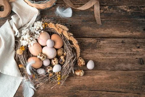 Happy Easter, festive background with eggs in a nest on a wooden background. Stock Photos