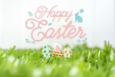 Happy easter with glass rabbit eggs on green grass field at white fence in ba Stock Photos