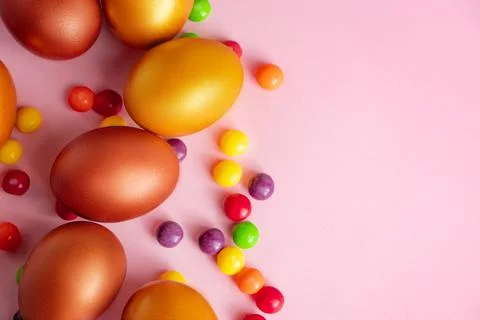 Happy Easter. Gold eggs and candies on a pink background. Stock Photos