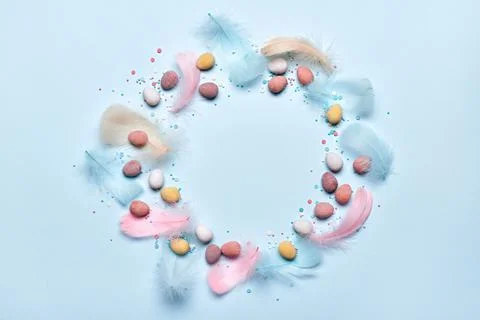 Happy easter greeting card. Round frame made of colorful feathers and chocolate Stock Photos