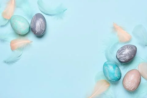 Happy easter greeting card template. Easter eggs and feathers on a blue pastel Stock Photos