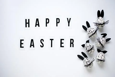 Happy Easter greeting on white background and Easter eggs, decorated as bunnies. Stock Photos