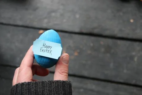 Happy easter. Hand holding an egg with tag. Copy space Stock Photos