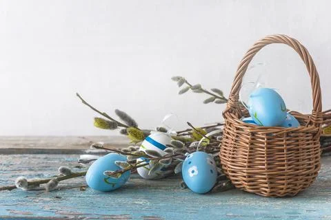 Happy easter holiday concept; Wicker basket with blue eggs and bouquet of w.. Stock Photos