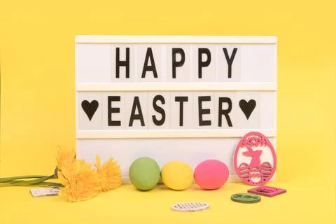 Happy Easter letters and easter eggs on yellow background Stock Photos