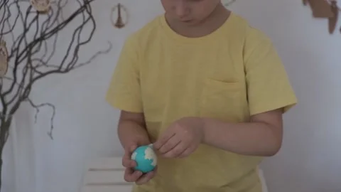 Happy Easter. Little boy peels the Easter egg Stock Footage 147950964